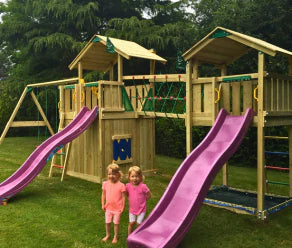 Spielturm aus Holz mit zwei Rutschen, Kletternetz, Netzbrücke und Schaukeln im Garten